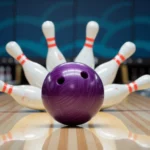 Egy lila kugli és néhány kidőlt bowlingpálca egy bowlingpályán.